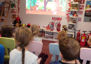 Dzieci oglądają film edukacyjny o przygodach Floriana strażaka.