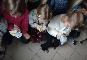 Dzieci jedzą słodkie bułki.