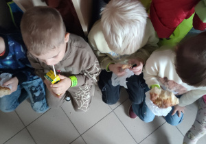 Dzieci jedzą słodkie bułki.
