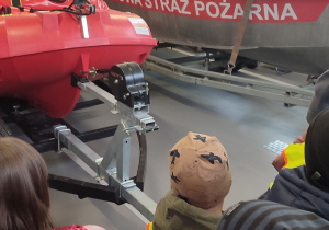 Dzieci oglądają łódź i ponton strażacki wykorzystywany do akcji na wodzie.