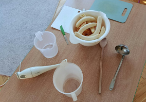 Narzędzia i produkty do wykonania musu: blender, deski, nożyki, łyżki, miski, owoce.