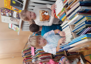 dzieci wybierają książki z półki