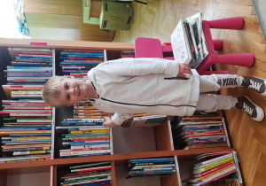 chłopiec stoi przed regałem na książki