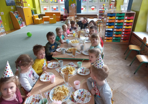 Dzieci biesiadują przy stolikach
