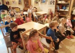 dzieci siedzą przy stolikach i oczekują na przedstawienie