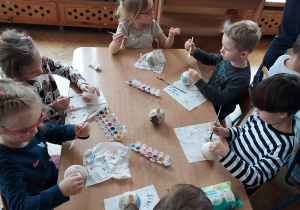Dzieci malują farbami ceramiczne bombki