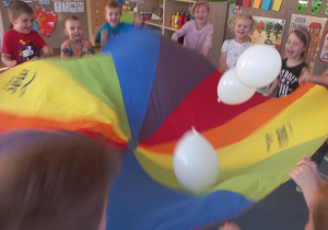Dzieci podczas wspólnej zabawy z chustą animacyjną i balonami