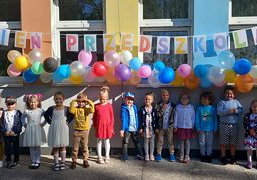 Dzieci pozują do zdjęcia grupowego na tle napisu "Dzień Przedszkolaka"