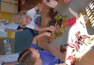 Dziewczynki przyklejają liście na pracy plastycznej