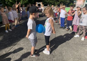Dziewczynka i chłopiec tańczą z balonem