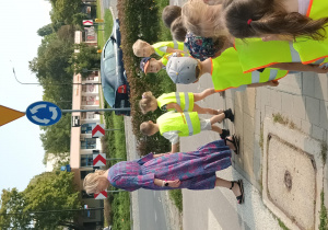 Dzieci stoją z nauczycielką przed przejściem dla pieszych.