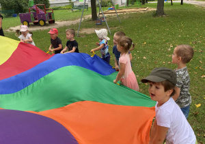 Dzieci bawią się chustą animacyjną w ogrodzie przedszkolnym