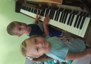 Dziewczynka i chłopiec grają na pianinie