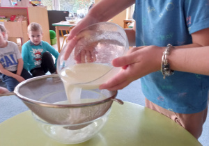 Chłopiec przelewa mleko z octem przez sitko