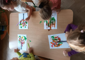 Dzieci za pomocą słomki rozdmuchują plamy z farby w ten sposób powstaje jesienne drzewo.