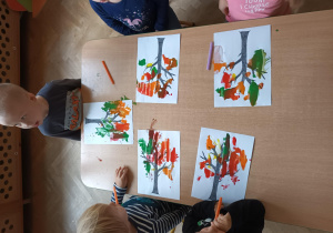 Dzieci za pomocą słomki rozdmuchują plamy z farby w ten sposób powstaje jesienne drzewo.
