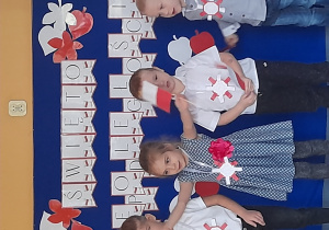 Przedszkolaki stoją na tle dekoracji z okazji Dnia Niepodległości