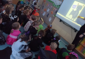 Dzieci poznają nowe słówka po angielsku oglądając ilustracje na tablicy interaktywnej i powtarzając słowa po nauczycielce