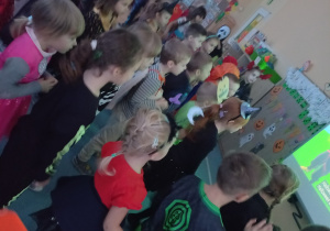Dzieci tańczą przebrane w stroje halloweenowe do piosenki prezentowanej na tablicy interaktywnej