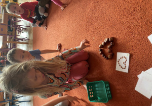 Dziewczynka układa z kasztanów według wzoru