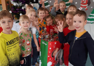 Dzieci pozują do zdjęcia przy prezentach od Mikołaja