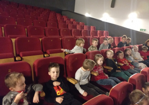 Dzieci czekają siedząc w fotelach na rozpoczęcie filmu