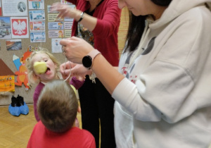 Dzieci biorą udział w konkursie na zjadanie wiszącego jabłka
