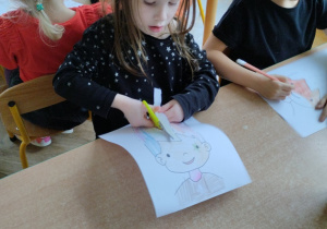 Dziewczynka wycina włosy postaci z papieru