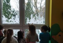 Dzieci machają przez okno do Mikołaja.