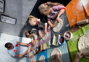 Dzieci własnoręcznie wałkują ciasto na pizzę