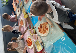 Dzieci smarują ciasto na pizzę sosem