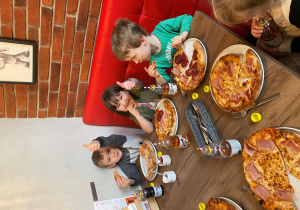Dzieci jedzą własnoręcznie przygotowaną pizzę