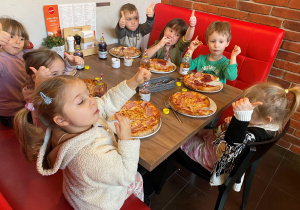 Dzieci jedzą własnoręcznie przygotowaną pizzę