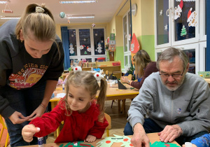 Dzieci wraz z rodzicami i dziadkami wykonują świąteczny papierowy wieniec
