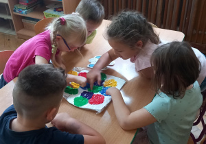 Dzieci rozsmarowują palcami farby, które łączą się ze sobą