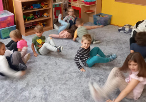 dzieci siedząc na podłodze obracają się wokół własnej osi