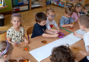 Dzieci malują farbami liście