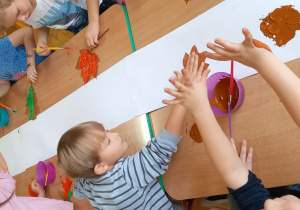 Dzieci odbijają pomalowane liście na kartonie
