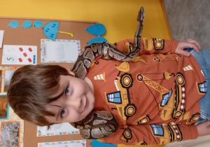 Chłopiec trzyma węża na szyi