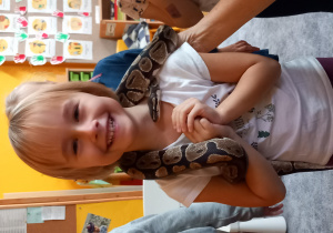 Dziewczynka cieszy się trzymając węża na szyi