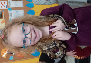 Dziewczynka cieszy się trzymając węża na szyi