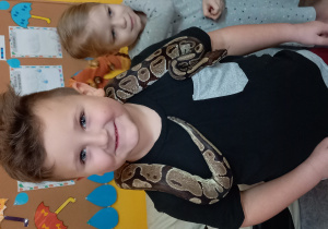 Chłopiec trzyma węża na szyi