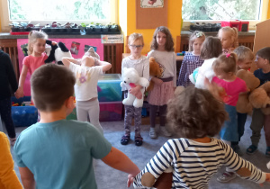 Dzieci tańczą w kole ze swoimi misiami