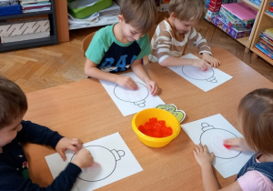 Dzieci malują kostkami lodu emblemat bombki