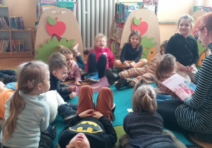 Dzieci siedząc lub leżąc na dywanie słuchają baśni "Kopciuszek"