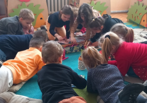 Dzieci leżąc na dywanie kolorują odnaleziony pantofelek