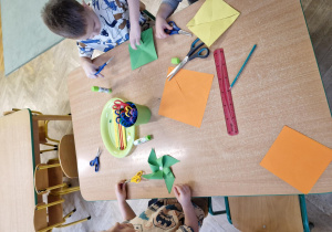 Dzieci wykonują wiatraczki z papieru i słomek do napojów.