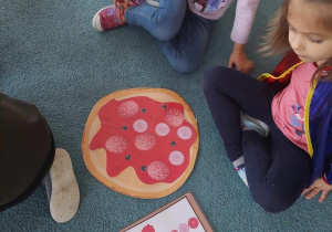 Dziewczynki prezentują swoją pizzę ułożoną zgodnie z podanymi składnikami