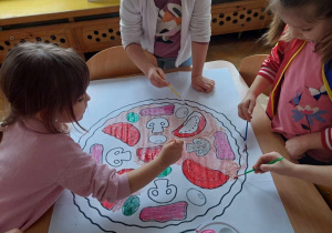 Dziewczynki wspólnie malują kontur pizzy
