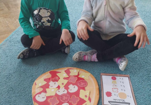Dzieci prezentują swoją pizzę ułożoną zgodnie z podanymi składnikami